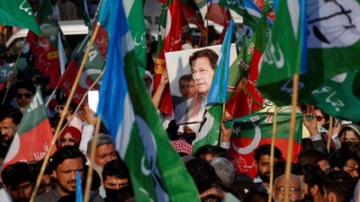 A portrait of the former Prime Minister Imran Khan is seen amid flags of Pakistan Tehreek-e-Insaf (PTI) (Reuters)