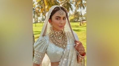 Rakul Preet's mirror-work ivory lehenga set features a cropped choli, a floor-length lehenga skirt, and two dupattas. While the blouse has a sweetheart neckline, puffed half-length sleeves, pearl embroidery on the hem, mirror embellishments, and a fitted design, the lehenga has an A-line silhouette, heavy layered and pleated ghera, and mirror adorned in intricate patterns. She wore the matching mirror-embroidered dupatta like a saree pallu and draped another net veil over her head forming a train at the back. (Instagram/@stylebyami) Rakul Preet's mirror-work ivory lehenga set features a cropped choli, a floor-length lehenga skirt, and two dupattas. While the blouse has a sweetheart neckline, puffed half-length sleeves, pearl embroidery on the hem, mirror embellishments, and a fitted design, the lehenga has an A-line silhouette, heavy layered and pleated ghera, and mirror adorned in intricate patterns. She wore the matching mirror-embroidered dupatta like a saree pallu and draped another net veil over her head forming a train at the back. (Instagram/@stylebyami)