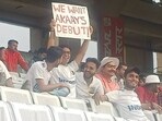 The image shows the cricket fan holding up a placard that has a request for Virat Kohli and Anushka Sharma. The image shows the cricket fan holding up a placard that has a request for Virat Kohli and Anushka Sharma.