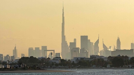 A man and a child ride a personal watercraft near the Dubai skyline featuring the landmark Burj Khalifa skyscraper, the world�s tallest building, on February 13, 2024. (Photo by Giuseppe CACACE / AFP)