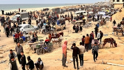 Palestinians gather as they wait for trucks carrying bags of flour to arrive, near an Israeli checkpoint (REUTERS)