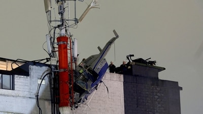 The helicopter hangs from the roof of a building after crashing due to strong winds, according to authorities, in Medellin, Colombia. (REUTERS)