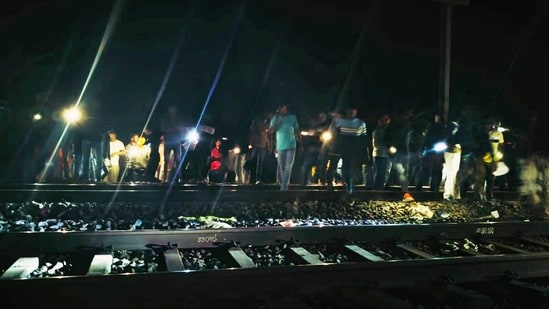People stand near a railway track where at least two persons were run over and killed by a train near Kaljharia area, in Jamtara district. (PTI)