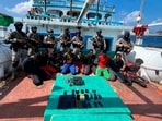 Commandos stand guard with a group of detained pirates after the Indian Navy freed a hijacked fishing vessel. (AP)