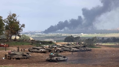 Israel-Hamas War: Israeli soldiers stand next to tanks at a position in Israel near the border with the Gaza Strip as smoke billows over the Gaza Strip after Israeli bombardment. (AFP)