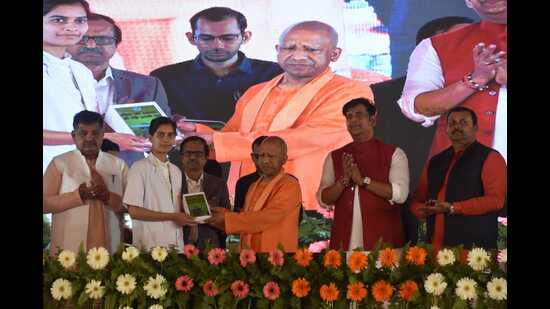 UP chief minister Yogi Adityanath giving a tablet to a student at an event in Gorakhpur on March 3. (HT photo)