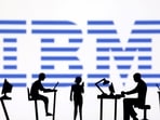 Figurines with computers and smartphones are seen in front of IBM logo.