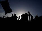 Palestinians are silhouetted as they inspect the damage following an Israeli airstrike