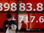 A man uses his smartphone in front of an electronic screen displaying Japan's Nikkei share average as the share average climbed to a record high outside a brokerage in Tokyo, Japan.