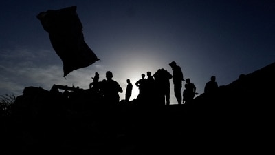 Palestinians are silhouetted as they inspect the damage following an Israeli airstrike (REUTERS)