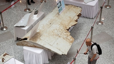 A visitor looks at the wreckage of an aircraft believed to be from the missing Malaysia Airlines flight MH370 during a remembrance event (REUTERS)