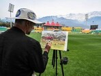 Andy Brown, a British artist, paints the cricket field during a practice session at the Himachal Pradesh Cricket Association Stadium in Dharamsala Andy Brown, a British artist, paints the cricket field during a practice session at the Himachal Pradesh Cricket Association Stadium in Dharamsala
