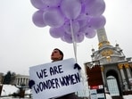 FILE - A woman holds balloons and a poster to mark International Women's Day in central Kiev, Ukraine, March 8, 2018. Women across the world will demand equal pay, reproductive rights, education, justice and other essential needs during demonstrations marking International Women’s Day on Friday, March 8, 2024. (AP Photo/Efrem Lukatsky, File)