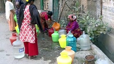 People wait for their turn to fill their gallons with running water. People wait for their turn to fill their gallons with running water.