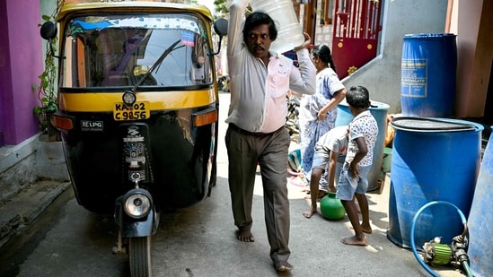 An autorickshaw driver carries a can of water filled from a municipal tap, amid an ongoing water crisis in Bengaluru on March 7, 2024. (Photo by Idrees MOHAMMED / AFP) (AFP)
