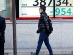 A person walks in front of an electronic stock board showing Japan's Nikkei 225 index at a securities firm.