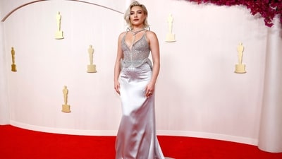 Florence Pugh poses on the red carpet at the Oscars in a stunning silver metallic dress by Del Core. Her chic outfit features a plunging neckline, sheer crystal embellished fabric and an uneven hemline. She finished off her glamorous look with a satin bodycon skirt and a striking silver metallic neckpiece. (REUTERS)