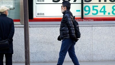 A person walks in front of an electronic stock board showing Japan's Nikkei 225 index at a securities firm. (AP)