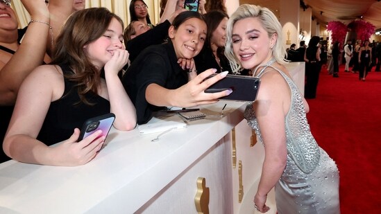 Florence Pugh poses for a photo with spectators on the red carpet. She was not nominated this year but her film Oppenheimer won Best Picture.(REUTERS)