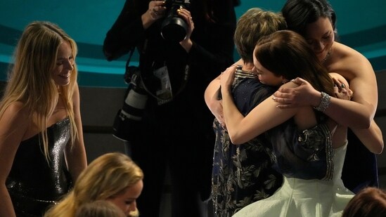 Margot Robbie looks on as Emma Stone hugs her co-nominees in Best Actress category Lily Gladstone and Annette Bening.