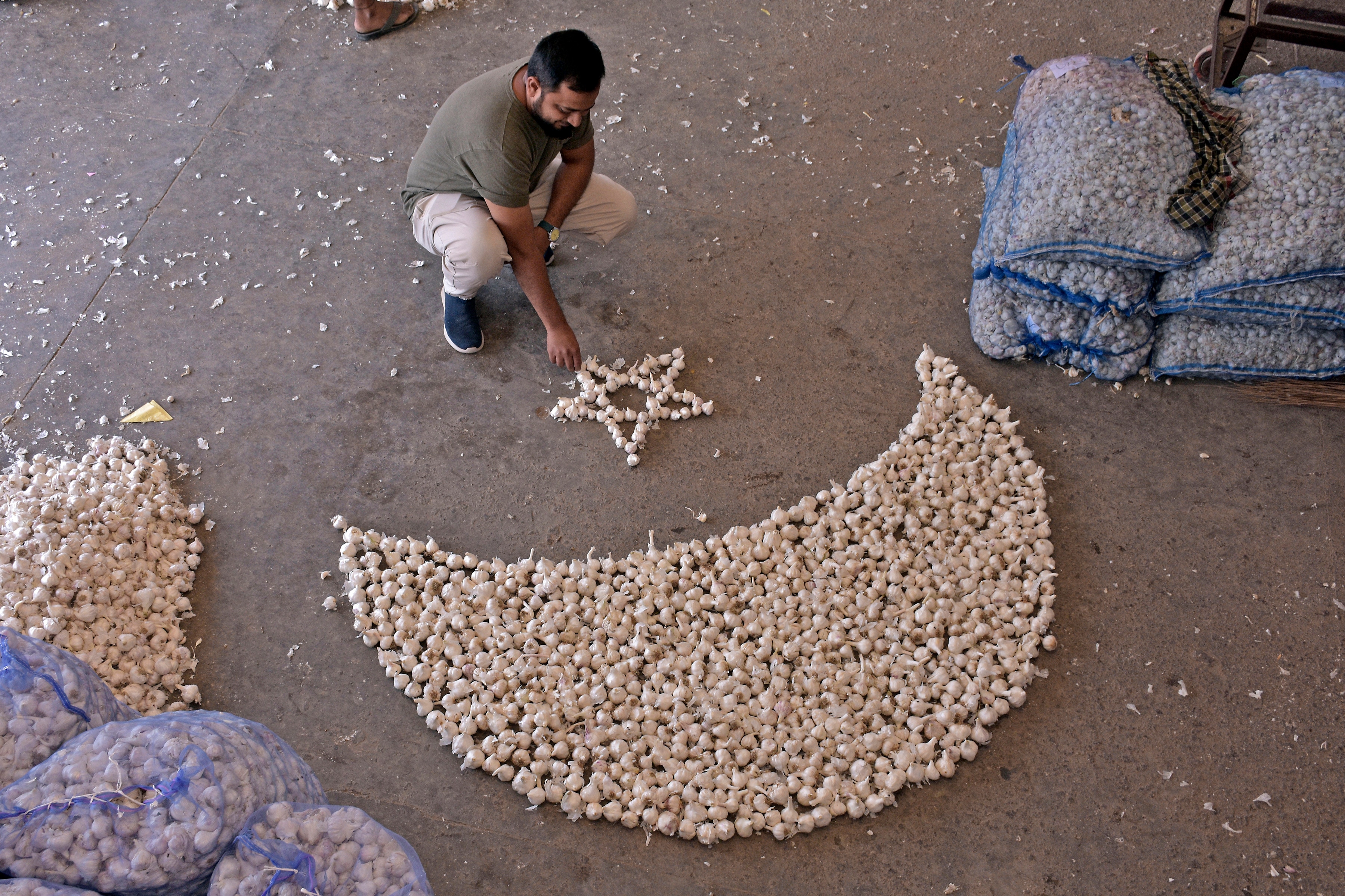 Ramadan 2024 India Moon Sighting Live: A garlic wholesaler makes Half Moon with Star as preparations begin on the eve of the Ramadan month, at a market in Surat on Monday. (ANI Photo/Ashok Munjani) Ramadan 2024 India Moon Sighting Live: A garlic wholesaler makes Half Moon with Star as preparations begin on the eve of the Ramadan month, at a market in Surat on Monday. (ANI Photo/Ashok Munjani)