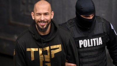 A police officer escorts Andrew Tate, center, handcuffed, from the Court of Appeal in Bucharest, Romania, Tuesday, March 12, 2024. Online influencer Andrew Tate was detained in Romania and handed an arrest warrant issued by British authorities, his spokesperson said Tuesday. (AP Photo/ Alexandru Dobre) (AP) A police officer escorts Andrew Tate, center, handcuffed, from the Court of Appeal in Bucharest, Romania, Tuesday, March 12, 2024. Online influencer Andrew Tate was detained in Romania and handed an arrest warrant issued by British authorities, his spokesperson said Tuesday. (AP Photo/ Alexandru Dobre) (AP)