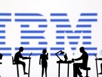 IBM layoffs: Figurines with computers and smartphones are seen in front of IBM logo. The company reportedly announced job cuts.