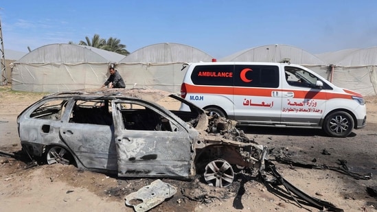 An ambulance drives past a car that was destroyed by Israeli bombardment in Rafah in the southern Gaza Strip. (AFP)