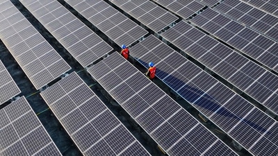 TOPSHOT - This photo taken on February 21, 2024 shows workers inspecting solar panels at a rooftop of a power plant in Fuzhou, in southern China's Fujian province. (Photo by AFP) / China OUT (AFP)