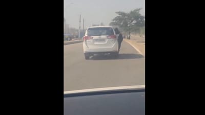 Snapshot of the woman hanging from moving car's door. (X/@Vivek K. Tripathi) Snapshot of the woman hanging from moving car's door. (X/@Vivek K. Tripathi)