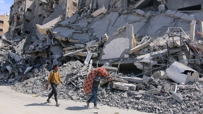 Palestinians pass destroyed buildings following the withdrawal of the Israeli military from Hamad City, west of Khan Younis, Gaza, on Wednesday, March 13, 2024. (Bloomberg) Palestinians pass destroyed buildings following the withdrawal of the Israeli military from Hamad City, west of Khan Younis, Gaza, on Wednesday, March 13, 2024. (Bloomberg)