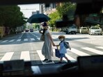 FILE - A pedestrian crossing a street with a child is seen through a taxi window in Tokyo, Monday, July 19, 2021. The number of babies born in Japan last year fell for an eighth straight year to a new low, government data showed Tuesday, Feb. 27, 2024, and a top official said it was critical for the country to reverse the trend in the coming half-dozen years. (AP Photo/David Goldman, File) FILE - A pedestrian crossing a street with a child is seen through a taxi window in Tokyo, Monday, July 19, 2021. The number of babies born in Japan last year fell for an eighth straight year to a new low, government data showed Tuesday, Feb. 27, 2024, and a top official said it was critical for the country to reverse the trend in the coming half-dozen years. (AP Photo/David Goldman, File)