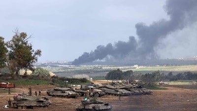 Israel-Hamas War: Israeli soldiers stand next to tanks at a position in Israel near the border with the Gaza Strip as smoke billows over the Gaza Strip after Israeli bombardment. (AFP)
