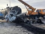 Security personnel and volunteers standing near the wreckage of burned passenger bus and oil tanker after they and a motorbike collided on the Herat-Kandahar highway in Grishk district of Helmand province