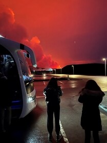 People who are being evacuated stand by a bus as a volcano erupts, in Grindavik, Iceland, (MELISSA EZAIR via REUTERS)