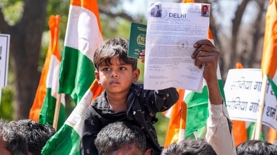 New Delhi: A child holds a passport during a protest by Hindu and Sikh refugees from Pakistan and Afghanistan at AICC headquarters over statements made by the INDIA opposition bloc leaders on the Citizenship (Amendment) Act (CAA), in New Delhi, Friday, March 15, 2024. (PTI Photo/Kamal Singh) (PTI03_15_2024_000062B) (PTI) New Delhi: A child holds a passport during a protest by Hindu and Sikh refugees from Pakistan and Afghanistan at AICC headquarters over statements made by the INDIA opposition bloc leaders on the Citizenship (Amendment) Act (CAA), in New Delhi, Friday, March 15, 2024. (PTI Photo/Kamal Singh) (PTI03_15_2024_000062B) (PTI)