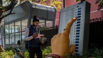 A man walks past a large model of a woman's finger pressing a button of an electronic voting machine displayed outside the office of the Election Commission of India (AP) A man walks past a large model of a woman's finger pressing a button of an electronic voting machine displayed outside the office of the Election Commission of India (AP)