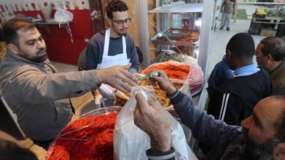 People queue to buy sfinz, a spongy fried bread that can be served plain or with eggs, in Tripoli, Libya, during the Muslim holy fasting month of Ramadan. Once an affordable street food eaten on the go, sfinz has become a luxury for many Libyans amid the soaring cost of living. (AFP) People queue to buy sfinz, a spongy fried bread that can be served plain or with eggs, in Tripoli, Libya, during the Muslim holy fasting month of Ramadan. Once an affordable street food eaten on the go, sfinz has become a luxury for many Libyans amid the soaring cost of living. (AFP)
