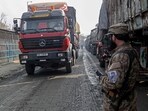 An Afghan security personnel stands guard as a truck arrives from Pakistan near the zero point Torkham border crossing between Afghanistan and Pakistan, in Nangarhar province on January 23, 2024. Pakistan and Afghanistan reopened a key trade crossing on January 23, officials on both sides said, after a row over travel papers as Islamabad cracks down on cross-border movements. Ties between the two countries have increasingly frayed in recent months, with Islamabad accusing the Taliban government of failing to root out militants staging attacks in Pakistan from their soil. (Photo by Shafiullah KAKAR / AFP)