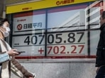 People walk past an electronic board showing a share price of the Nikkei index of the Tokyo Stock Exchange in Tokyo. People walk past an electronic board showing a share price of the Nikkei index of the Tokyo Stock Exchange in Tokyo.