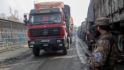 An Afghan security personnel stands guard as a truck arrives from Pakistan near the zero point Torkham border crossing between Afghanistan and Pakistan, in Nangarhar province on January 23, 2024. Pakistan and Afghanistan reopened a key trade crossing on January 23, officials on both sides said, after a row over travel papers as Islamabad cracks down on cross-border movements. Ties between the two countries have increasingly frayed in recent months, with Islamabad accusing the Taliban government of failing to root out militants staging attacks in Pakistan from their soil. (Photo by Shafiullah KAKAR / AFP) (AFP)