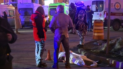 People stand at a body of a victim near the burning building of the Crocus City Hall on the western edge of Moscow, Russia, Friday, March 22, 2024. (AP) People stand at a body of a victim near the burning building of the Crocus City Hall on the western edge of Moscow, Russia, Friday, March 22, 2024. (AP)