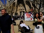 Tourists are seen next to a sign at Sagrada Familia Basilica alerting them of severe drought in Spain's northeastern region and urging them to save water due to low reservoir levels, as Catalonia declares state of emergency, in Barcelona, Spain. Tourism in Barcelona unaffected by drought restrictions, Easter holiday visitors can enjoy their stay 