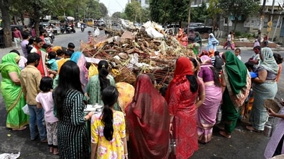 During Holika Dahan, devotees walk and pray around bonfires carrying vessels full of water. In this photo, devotees can be seen offering prayers during the festival at Sector 22, in Noida. (HT Photo/Sunil Ghosh)