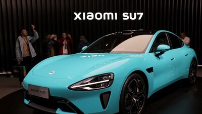 Visitors film around Xiaomi's first electric vehicle, the SU7, displayed at an event in Beijing, China. (Reuters)