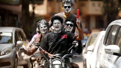Boys with their faces painted in silver ride a motorbike during Holi celebrations in Mumbai. (REUTERS)