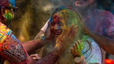 A girl has her face smeared with colored powder as people celebrate Holi. (AP)