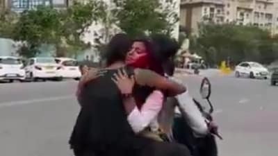 Two girls sitting facing each other on a two-wheeler driven by a boy as seen in this video. Two girls sitting facing each other on a two-wheeler driven by a boy as seen in this video.