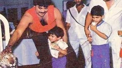 In this old picture, Chiranjeevi smiles and pets a leopard as a young Ram holds his father's leg. In this old picture, Chiranjeevi smiles and pets a leopard as a young Ram holds his father's leg.