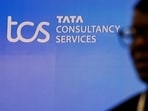 TCS hiring: A man walks past a logo of Tata Consultancy Services (TCS) before a press conference.